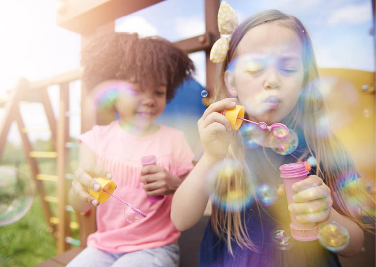 Two cute girls blowing the soap bubbles 