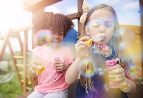 Two cute girls blowing the soap bubbles 